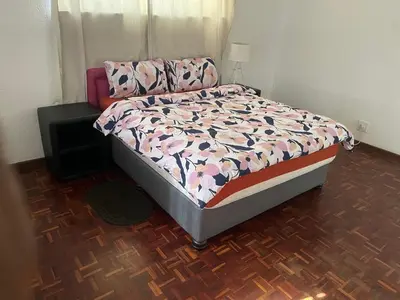 a bedroom with a bed with a floral comforter at Mary's Cape in Cape Town