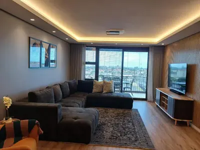 a living room with a couch and a flat screen tv at Capri 504, Island Club, Century City in Cape Town