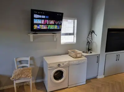 a laundry room with a washing machine and a tv at Spacious Lanes Cottage and Garage Parking in Cape Town