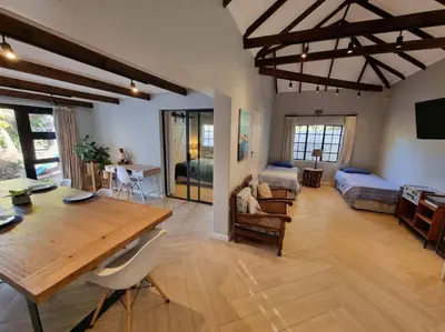 a living room with a wooden table and a bedroom at Spacious Lanes Cottage and Garage Parking in Cape Town