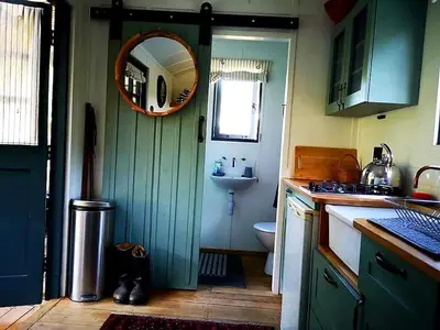 a bathroom with a green door and a sink at Babylons Tower Shepherds Hut in Mosselrivier