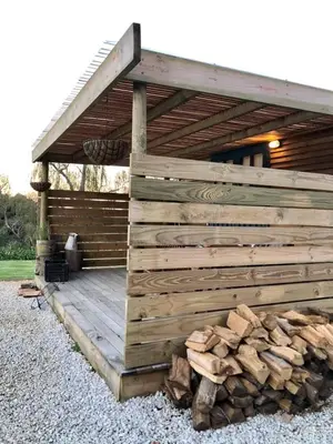 a wooden deck with a pile of fire wood at Babylons Tower Shepherds Hut in Mosselrivier