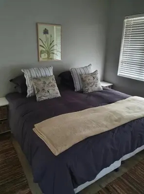 a bedroom with a large bed with purple sheets and pillows at Babylons Tower Cottage in Caledon