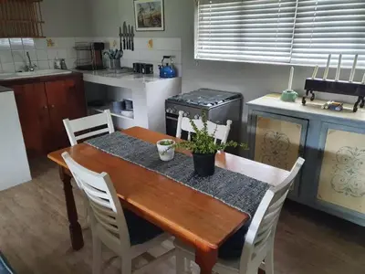 a kitchen with a wooden table with white chairs at Babylons Tower Cottage in Caledon