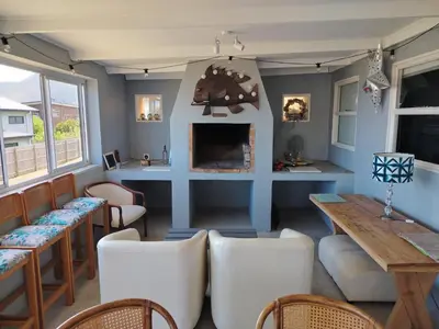 a room with a fireplace and a table and chairs at Sunset Splendour in Pringle Bay