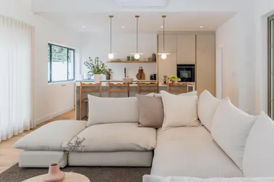 a living room with a white couch and a kitchen at Maison la Bruyere, 8p villa - heated pool, airco & hottub in Franschhoek