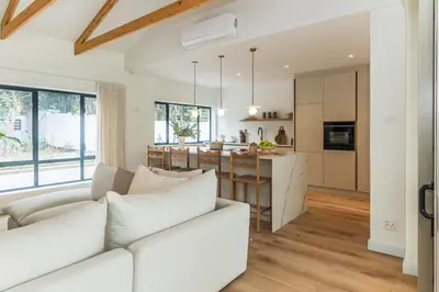 a living room with a white couch and a kitchen at Maison la Bruyere, 8p villa - heated pool, airco & hottub in Franschhoek