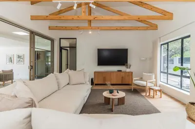 a living room with a white couch and a tv at Maison la Bruyere, 8p villa - heated pool, airco & hottub in Franschhoek