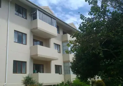 a white building with windows and a tree at A Short Walk to the Cliffs in Hermanus