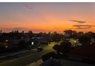 a sunset over a street with a car on the road at A Short Walk to the Cliffs in Hermanus