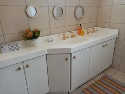 a bathroom with a white sink and two mirrors at Lighthouse Farm Backpackers Lodge in Cape Town