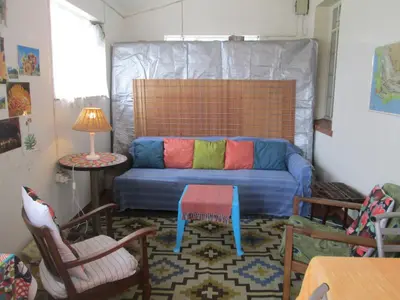 a living room with a couch and a table and chairs at Lighthouse Farm Backpackers Lodge in Cape Town