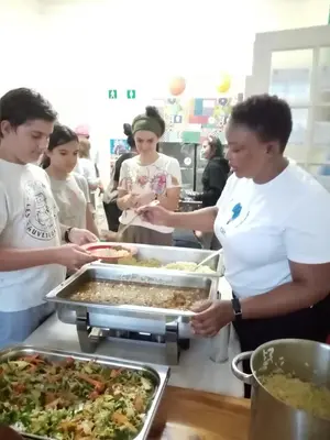a group of people preparing food in a kitchen at Lighthouse Farm Backpackers Lodge in Cape Town