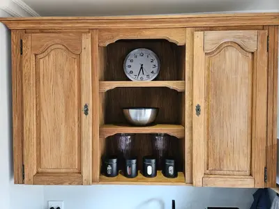 a wooden cabinet with a clock and some cups at Studio on Main in Hermanus