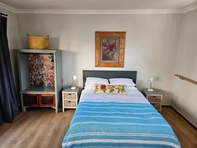a bedroom with a bed with a blue and white comforter at Studio on Main in Hermanus