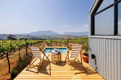 a deck with three chairs and a swimming pool at Stellenbosch Farm Cabin - Klein Frans in Stellenbosch