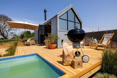 a house with a grill on a deck next to a pool at Stellenbosch Farm Cabin - Klein Frans in Stellenbosch