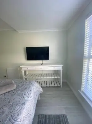 a bedroom with a bed and a desk with a television at 47 Whale Rock Estate in Hermanus