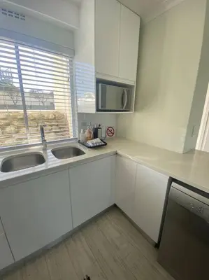 a white kitchen with a sink and a microwave at 47 Whale Rock Estate in Hermanus