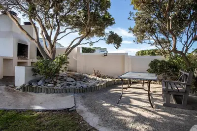 a picnic table and a bench in front of a fence at 47 Whale Rock Estate in Hermanus