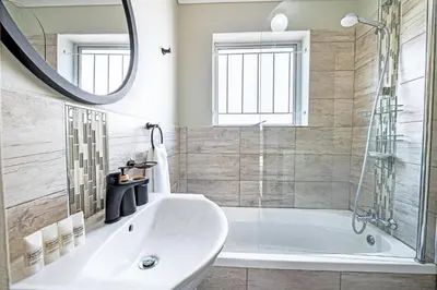 a white bathroom with a tub and a mirror at Cozy Garden Unit in Bloubergstrand in Bloubergstrand