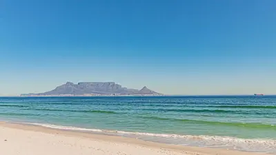 a view of the beach with an island in the distance at Cozy Garden Unit in Bloubergstrand in Bloubergstrand