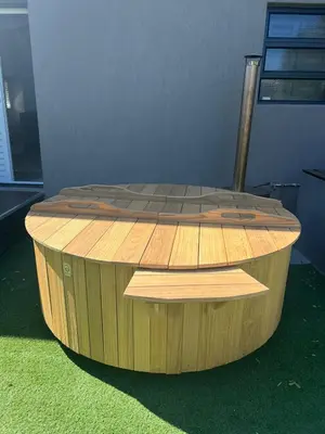 a circular wooden table sitting on top of green grass at Comfort Cove in Cape Town