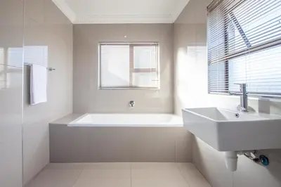 a white bathroom with a tub and a sink at West Gemini Guesthouse in Cape Town