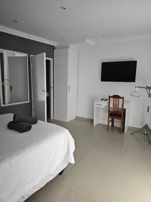 a bedroom with a bed and a desk and a television at West Gemini Guesthouse in Cape Town