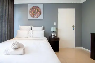 a bedroom with a white bed with a towel on it at West Gemini Guesthouse in Cape Town