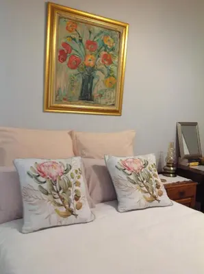 a bed with two pillows and a painting on the wall at The Pink Door in Caledon