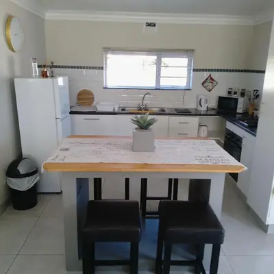 a kitchen with a table and some chairs and a refrigerator at 1 On Sonnet Unit Elaine in Cape Town