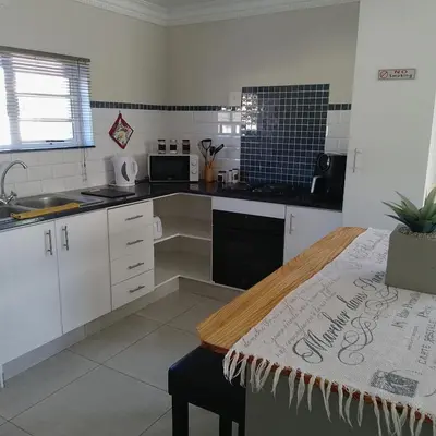 a kitchen with white cabinets and a table in it at 1 On Sonnet Unit Elaine in Cape Town