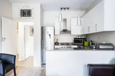a kitchen with white cabinets and a refrigerator at Avemore Vredehof 1 with backup power in Stellenbosch