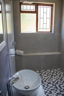 a bathroom with a toilet and a sink and a window at NamaStay in Cape Town