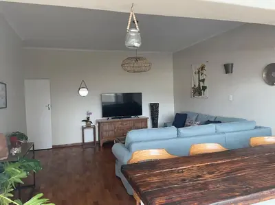 a living room with a blue couch and a tv at The Beachside Nest in Cape Town
