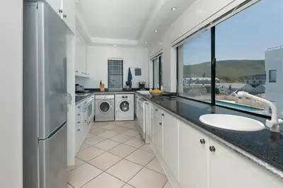 a bathroom with a sink and washing machines at Seafront Penthouse - Marine Court Hermanus in Hermanus