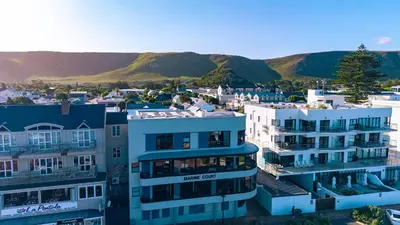 a city with buildings and mountains in the background at Seafront Penthouse - Marine Court Hermanus in Hermanus