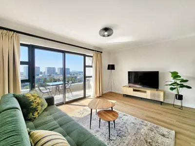 a living room with a green couch and a large window at Canal, Mountains, Sea Views, Pool, Gym, Parking, Wifi in Cape Town