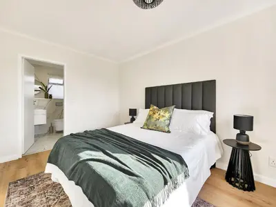 a bedroom with a large bed and a bathroom at Canal, Mountains, Sea Views, Pool, Gym, Parking, Wifi in Cape Town
