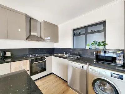 a kitchen with a washer and dryer in it at Canal, Mountains, Sea Views, Pool, Gym, Parking, Wifi in Cape Town