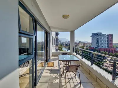 a balcony with a table and chairs and a view at Canal, Mountains, Sea Views, Pool, Gym, Parking, Wifi in Cape Town