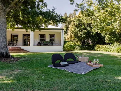 a blanket on the grass in front of a house at Keerweder Cottages in Franschhoek