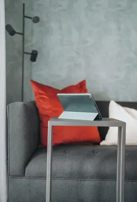 a laptop on a table on a couch with pillows at Calm Blouberg Beach Apt - Gated & Lift Access in Cape Town