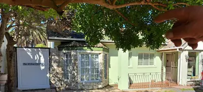 a house with a white door and a tree at The Willow Cottage in Cape Town