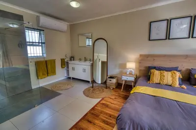 a bedroom with a bed and a shower and a mirror at Magnificent House in Cape Town