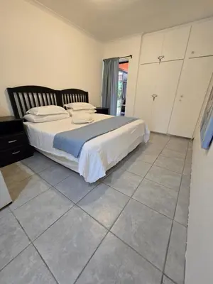 a bedroom with a bed and a tiled floor at Red Door Strand Guest house in Cape Town
