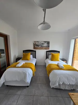 two beds in a room with yellow pillows at Red Door Strand Guest house in Cape Town