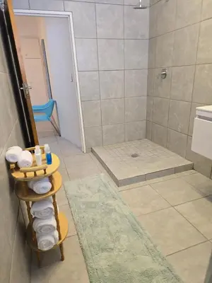 a bathroom with a shower and a rack with towels at Red Door Strand Guest house in Cape Town