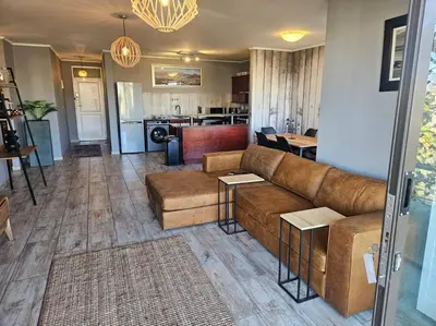 a living room with a couch and tables and a kitchen at SS Luxury Apartments Island Club in Cape Town